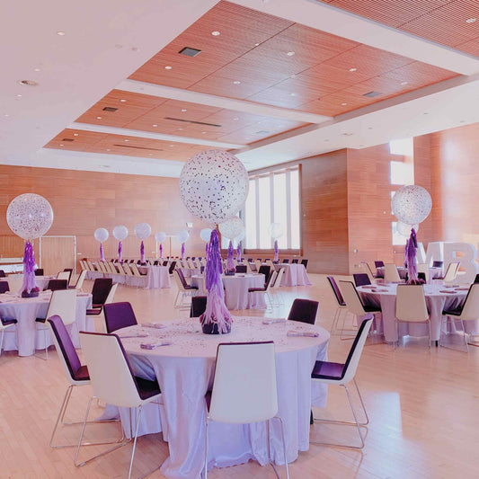 Modern conference room with round tables, chairs, and decorative balloons with confetti and tassels