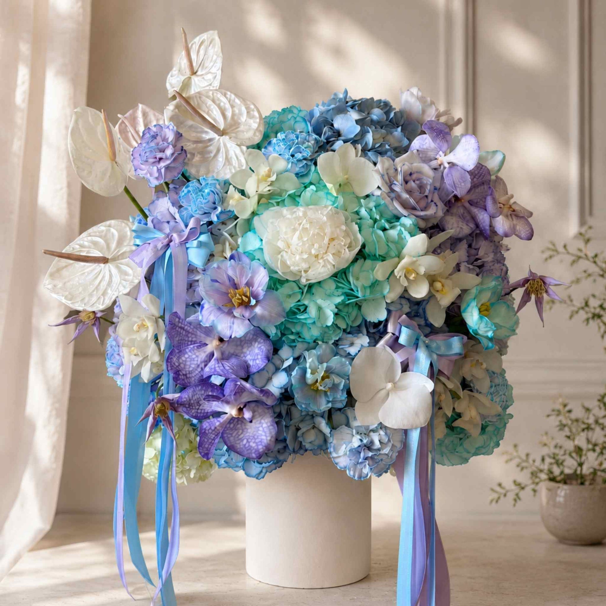 Colorful flower arrangement with ribbons in a white vase on a light wooden surface.