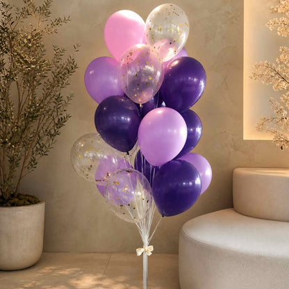 Bouquet of pink, purple, and clear balloons with LED lights in a room setting.