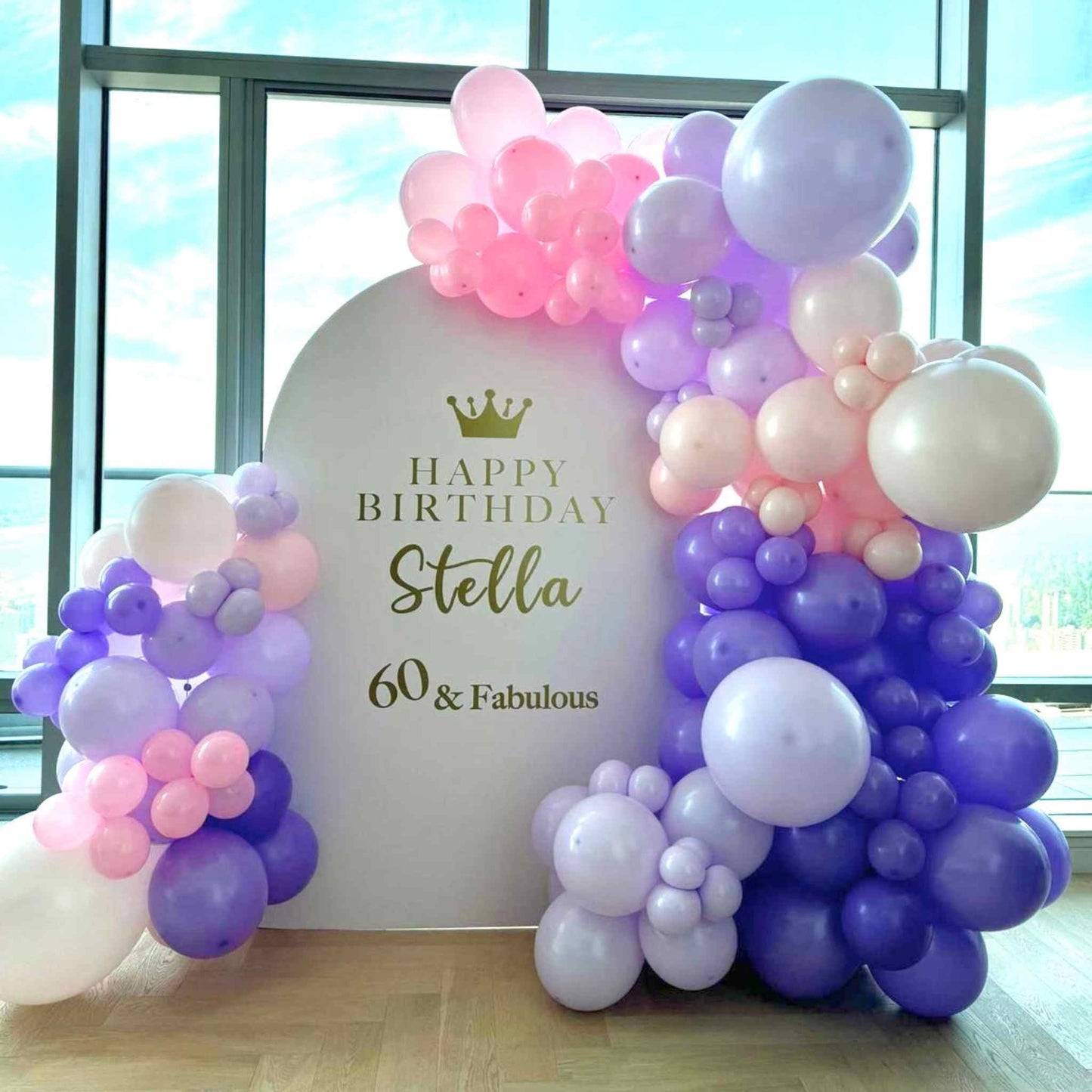Balloon arch with 'Happy Birthday Stella 60 & Fabulous' sign in front of a window.