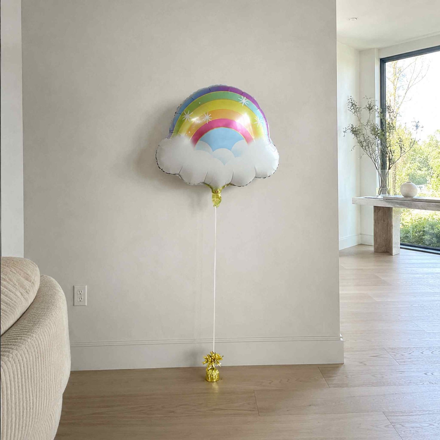 Rainbow cloud-shaped balloon in a room with a neutral color scheme.