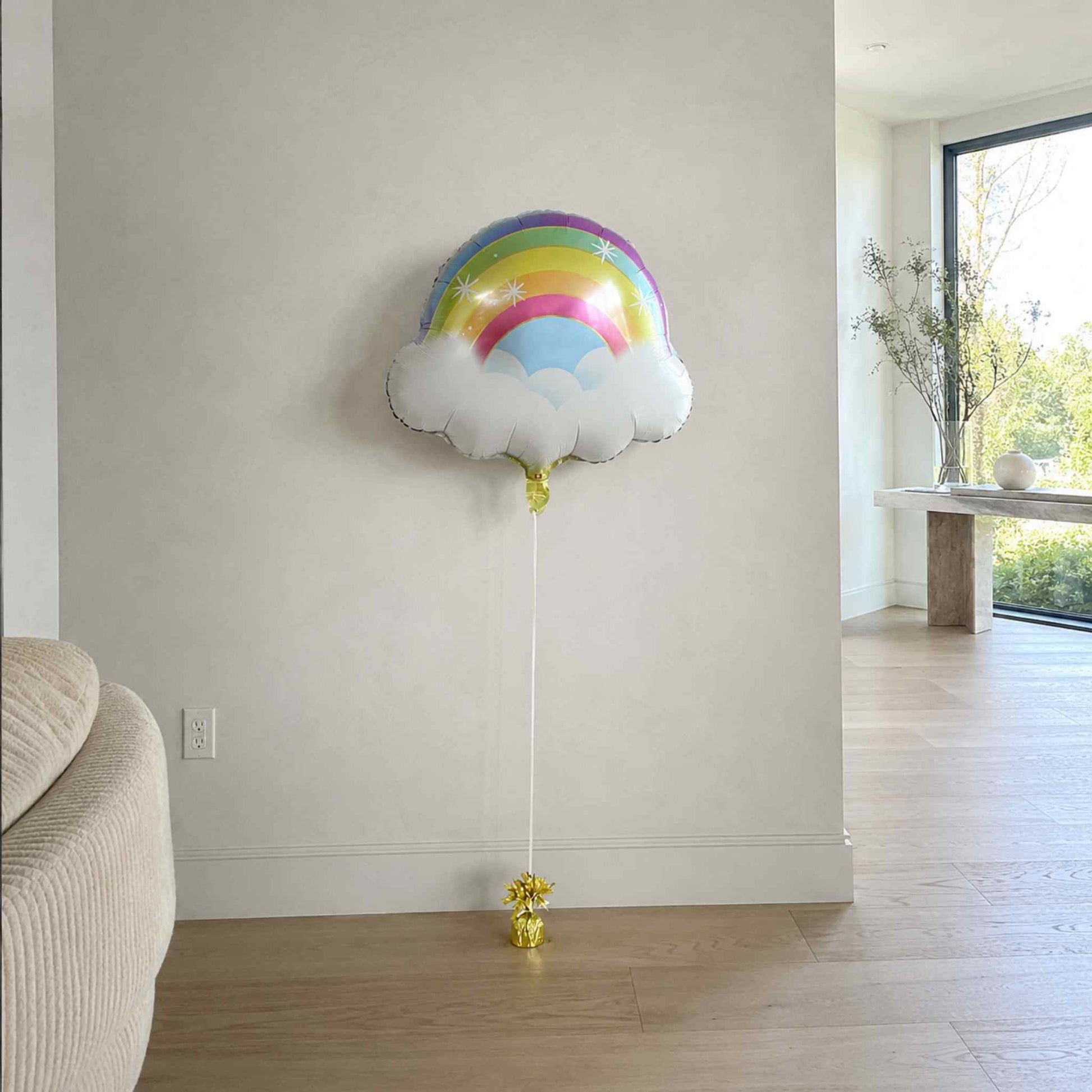 Rainbow cloud-shaped balloon in a room with a neutral color scheme.