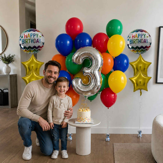 Man and child celebrating a birthday with colorful balloons and a cake.