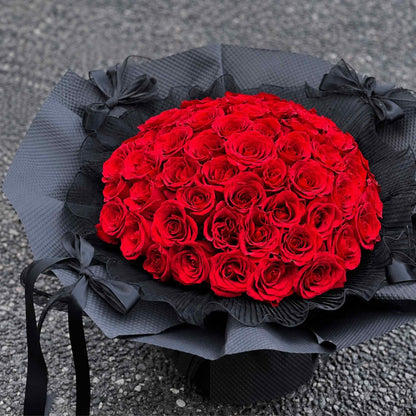 Bouquet of red roses wrapped in black paper on a textured surface