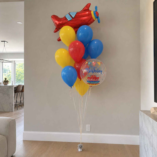 Colorful balloons with a red airplane-shaped balloon in a room.