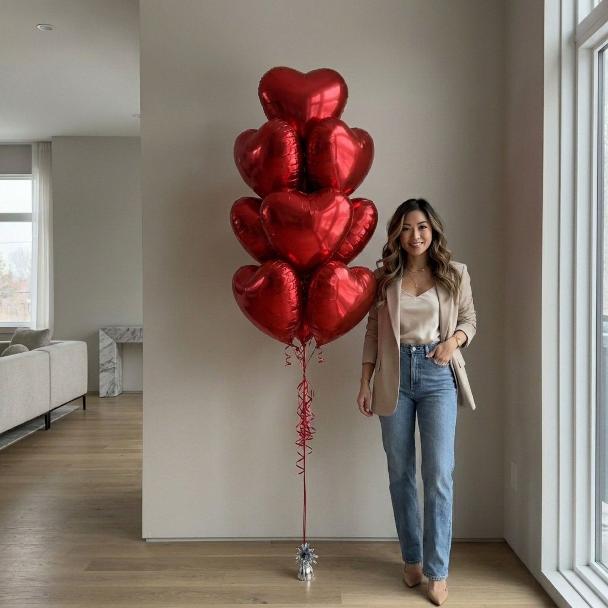 Woman standing by the red foil balloon bouquet. Large open floor apartment.
