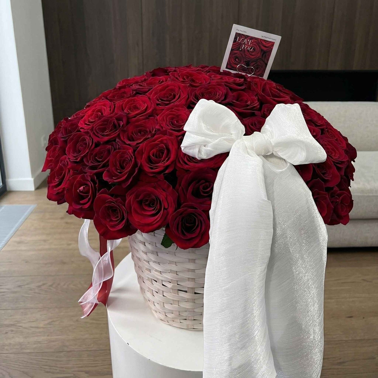 Bouquet of red roses with a white bow on a small table.