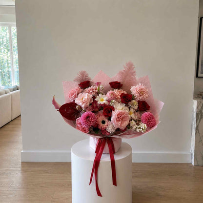 Bouquet of flowers on a white pedestal against a neutral wall.