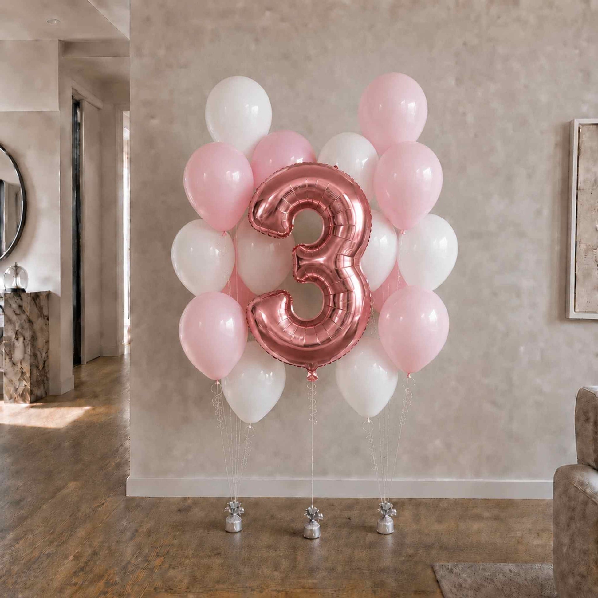 Balloon arrangement with a large number '3' balloon in a room setting.