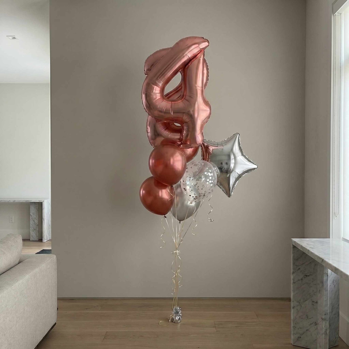 Decorative balloons shaped like the number '24' and a star in a living room setting.