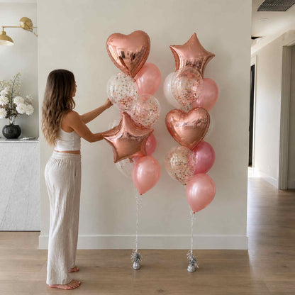 Woman arranging rose gold and pink balloons in a room.