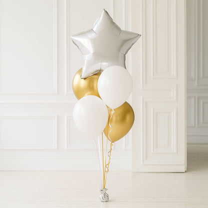 Decorative balloons including a silver star, gold, and white balloons against a white paneled wall.