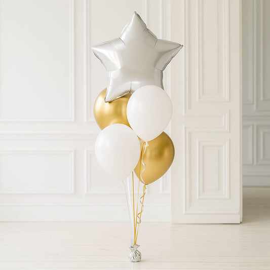 Decorative balloons including a silver star, gold, and white balloons against a white paneled wall.