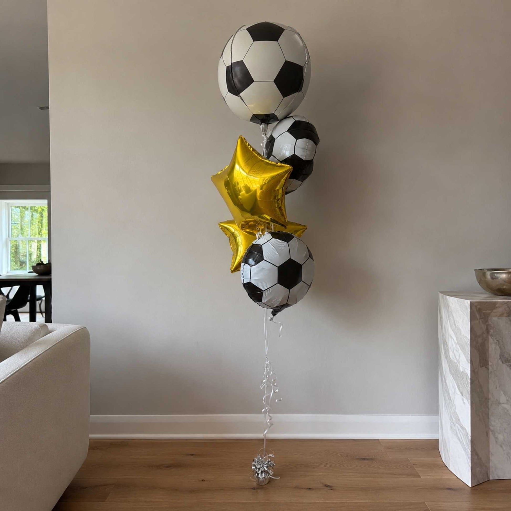Soccer ball and star-shaped balloons in a living room setting.