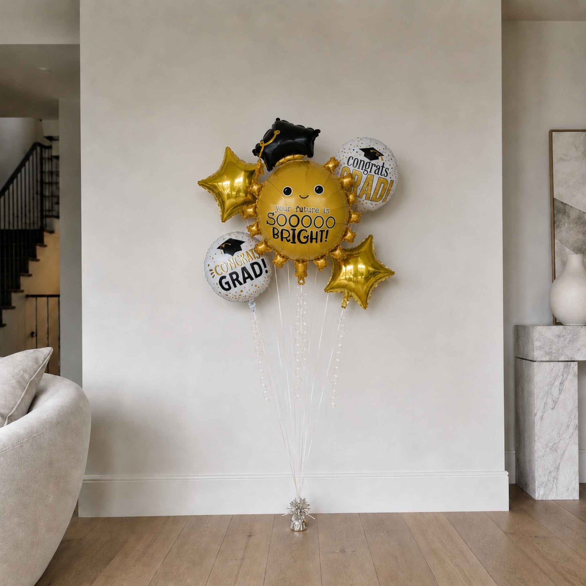 Graduation-themed balloons against a white wall in a living room.