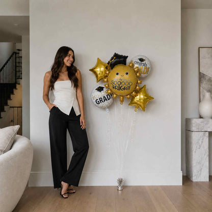 Woman standing next to a wall with graduation-themed balloons in a modern living room.