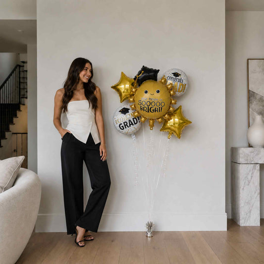 Woman standing next to a wall with graduation-themed balloons in a modern living room.