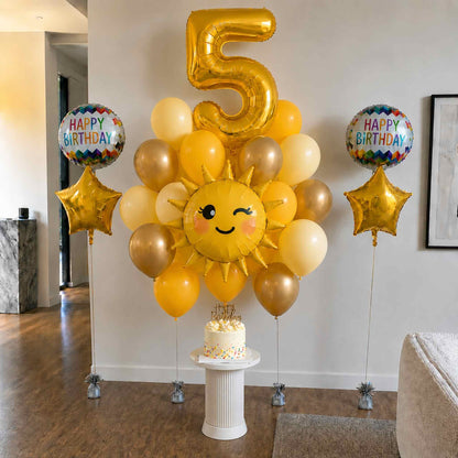 Birthday celebration setup with balloons, a cake, and a 'Happy Birthday' sign in a room.