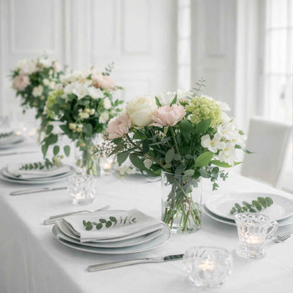 Elegant table setting with floral centerpieces and white tablecloth.