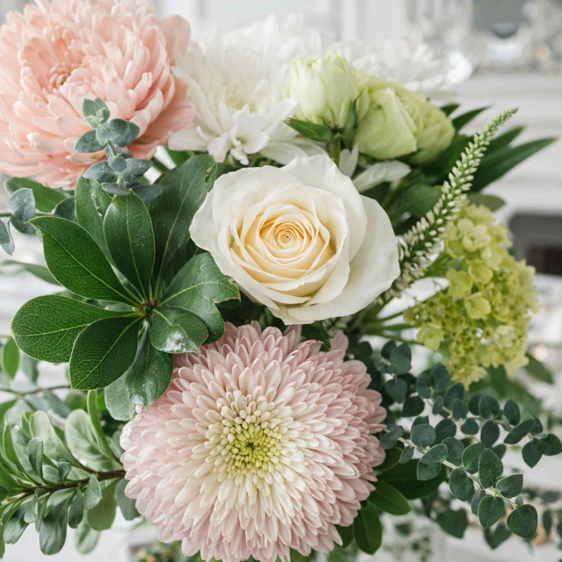 Bouquet of flowers including pink and white roses with greenery.