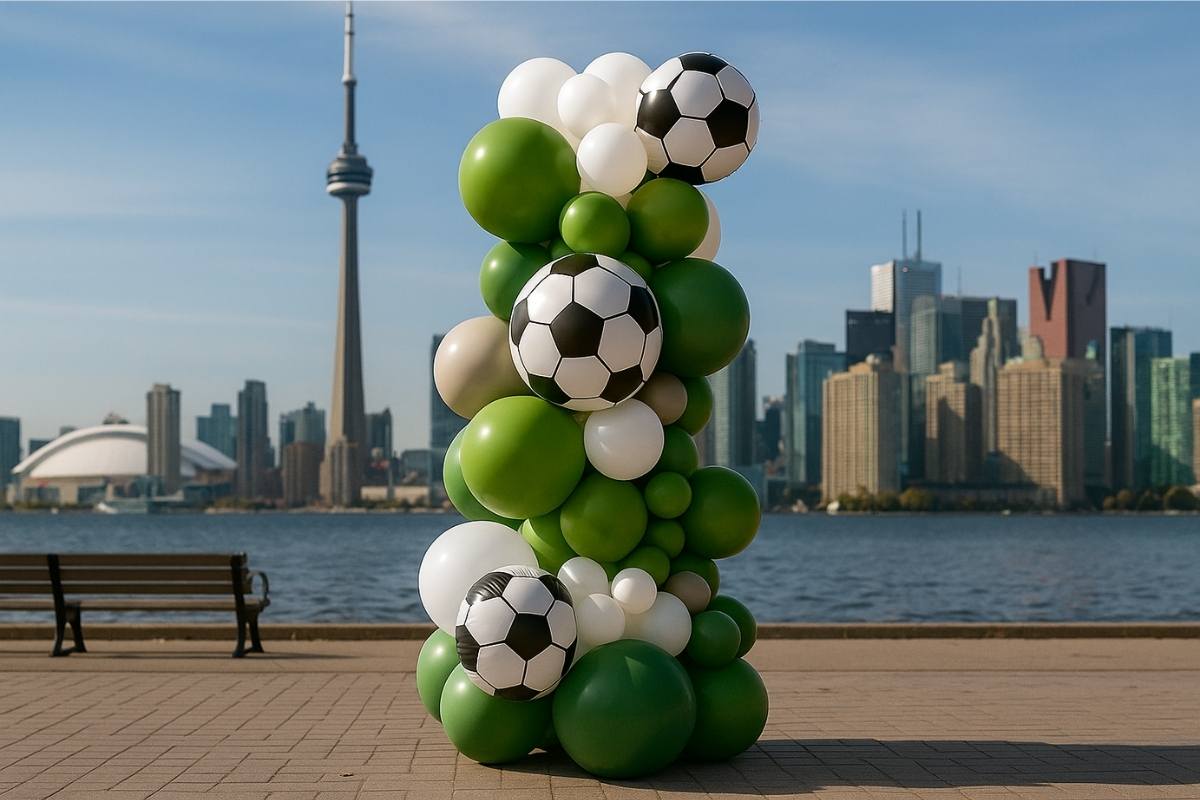 Balloon sculpture with soccer balls and green balloons in front of a city skyline