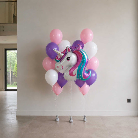 Unicorn-shaped balloon with pink, purple, and white balloons against a white wall.