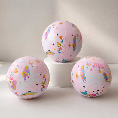 Three pink balloons with unicorn and rainbow designs on a white surface.
