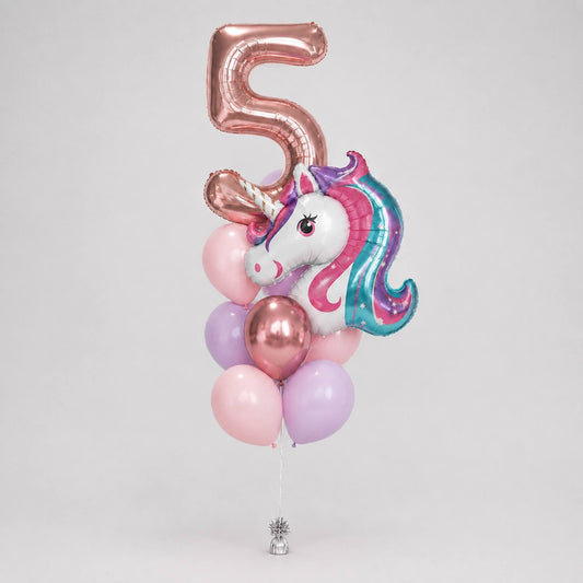 A balloon bouquet for a 5th birthday featuring a metallic rose gold foil balloon shaped like the number 5, a foil balloon of a white unicorn with a pink and teal mane, and several pastel pink, lavender, and rose gold latex balloons, all tied together with a silver string.
