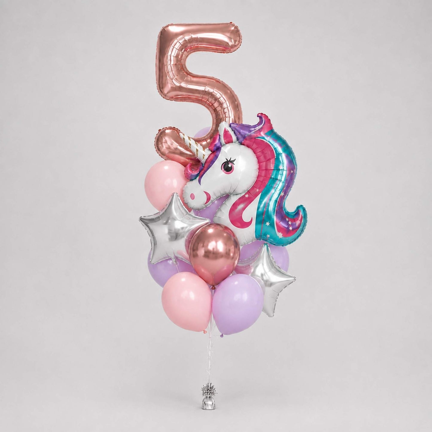 A balloon bouquet for a 5th birthday featuring a metallic rose gold number 5, a foil unicorn balloon with a pink and teal mane, pink, lavender, and metallic rose gold latex balloons, and two silver star balloons, set against a plain light gray background.
