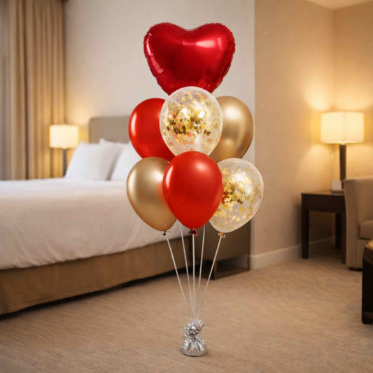 Bouquet of red, gold, and clear balloons in a hotel room setting.