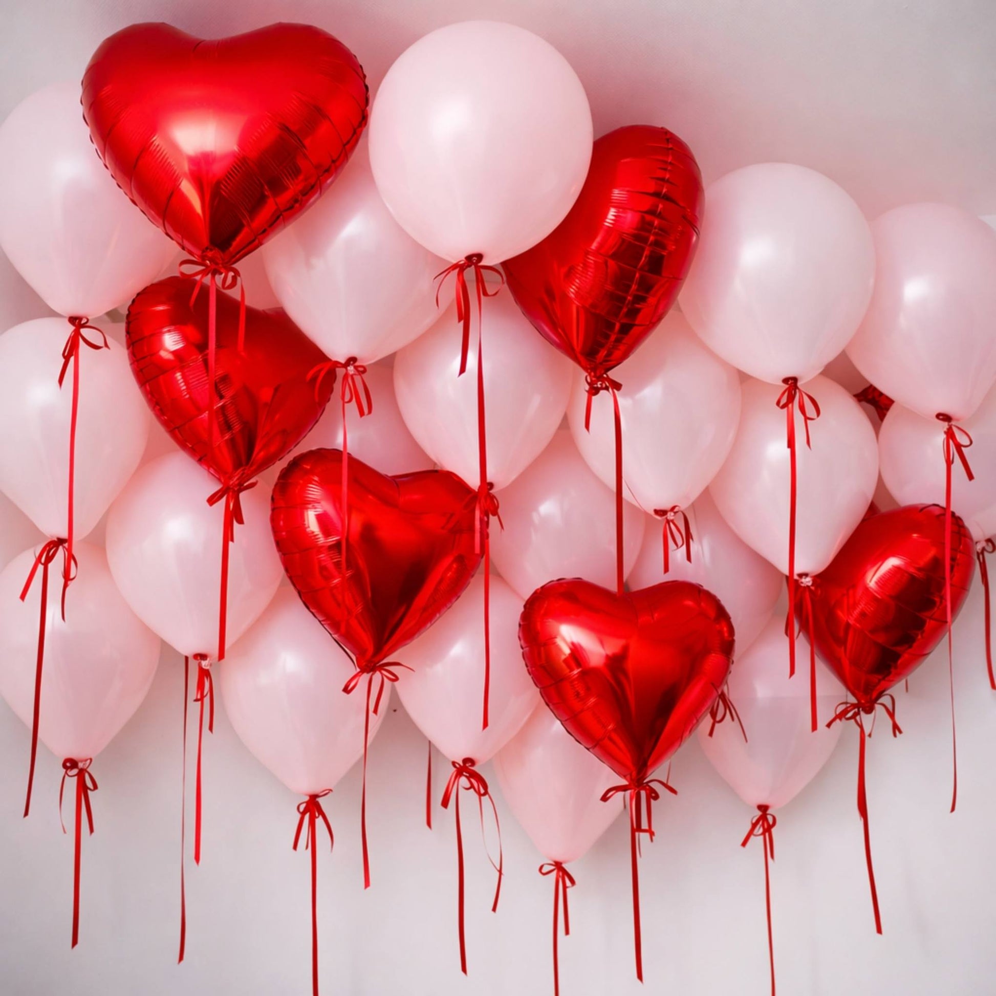 Heart-shaped balloons in red and pink on a white background