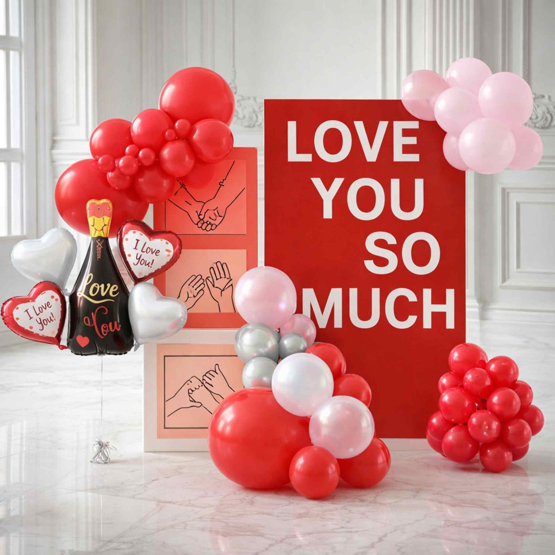 Decorative setup with balloons and 'Love You So Much' sign on a white wall.