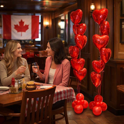 Two women at a restaurant table with heart-shaped balloons and a Canadian flag in the background.