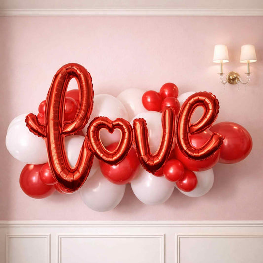 Red 'LOVE' balloon arrangement against a pink wall.