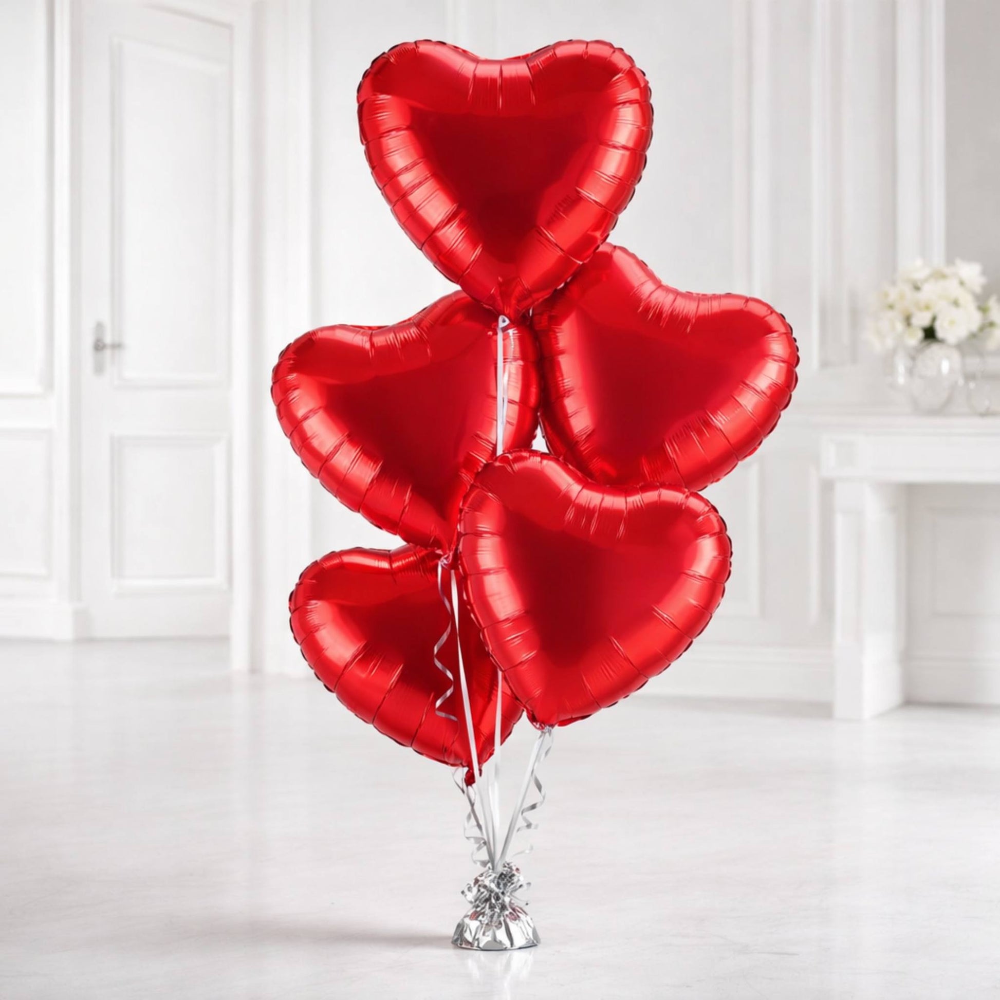 Red heart-shaped balloons on a stand against a white background