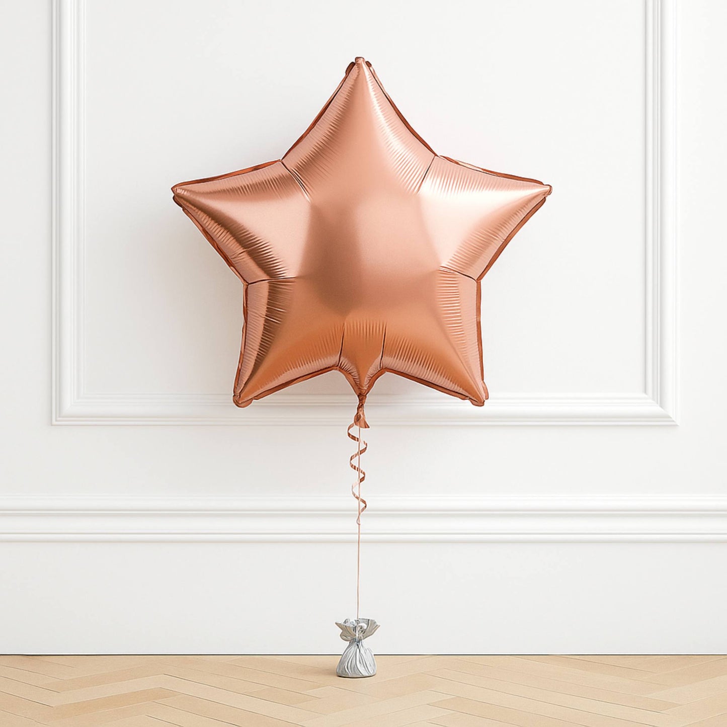 Rose gold star-shaped balloon against a white wall