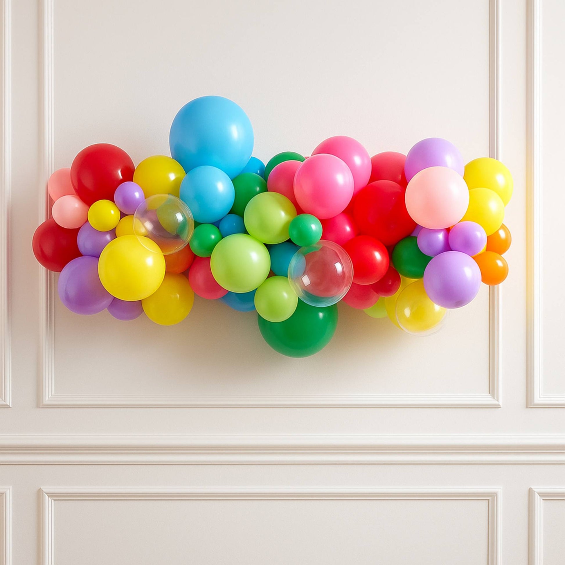 Colorful balloon arch against a white paneled wall