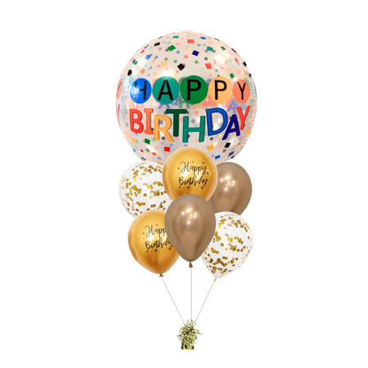 A bouquet of balloons featuring a large 'Happy Birthday' bubble balloon with multicolored confetti, accompanied by smaller balloons in gold and white with 'Happy Birthday' text.