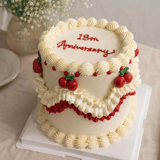 Classic vintage anniversary cake with white buttercream frosting, red cherry details, and elegant piped design for birthdays and celebrations.