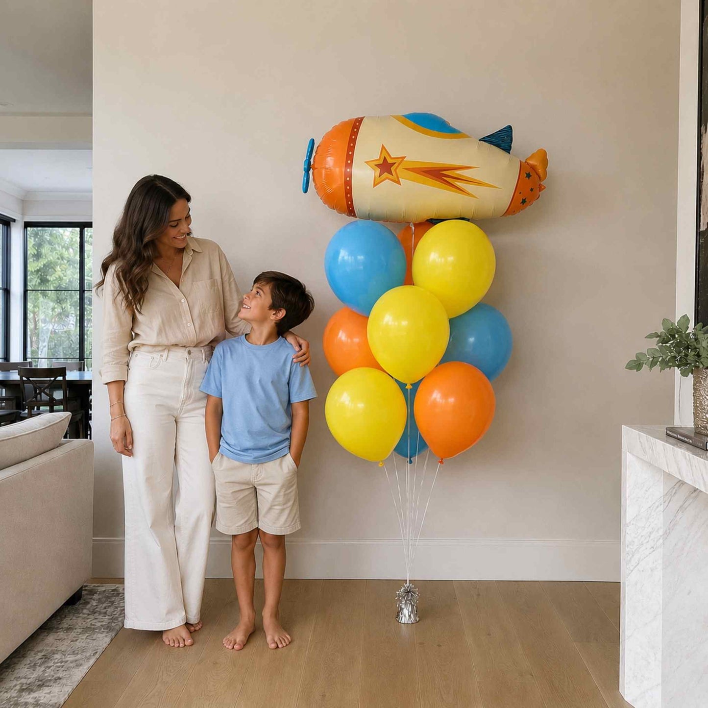 Woman and child standing next to a large cluster of colorful balloons shaped like a rocket.