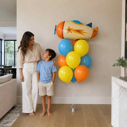 Woman and child standing next to a large cluster of colorful balloons shaped like a rocket.