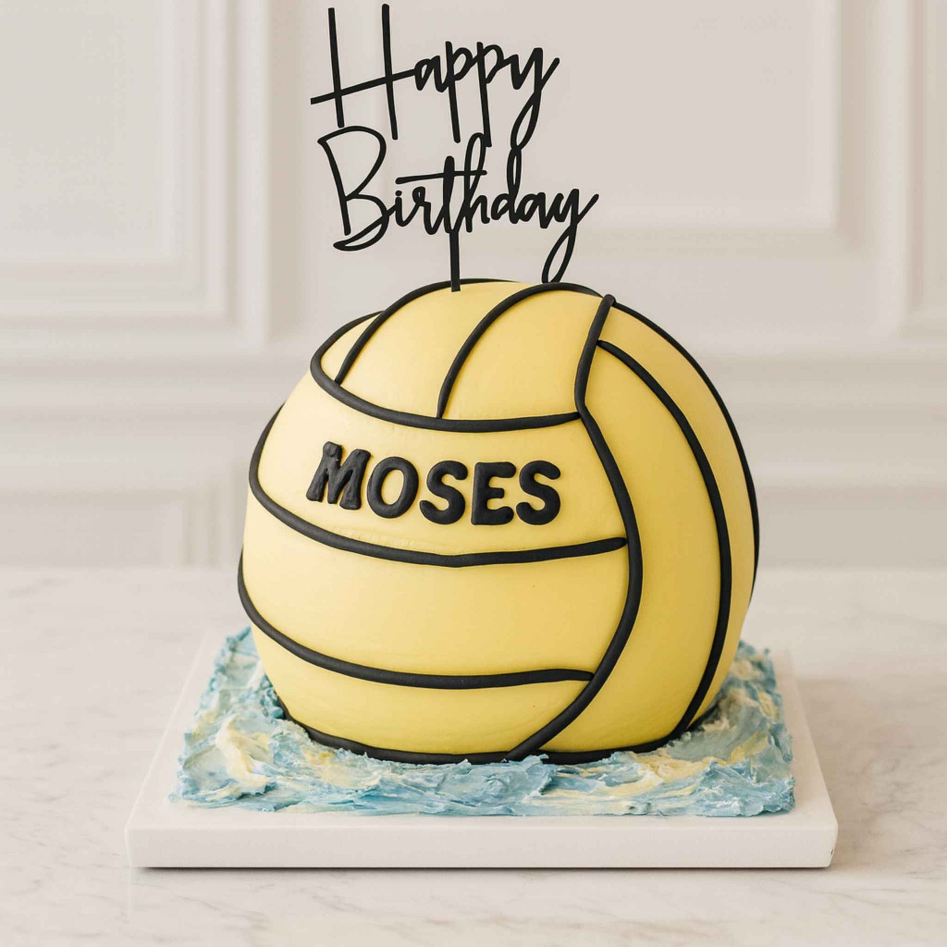 Birthday cake shaped like a water polo ball with 'Happy Birthday Moses' text on top.