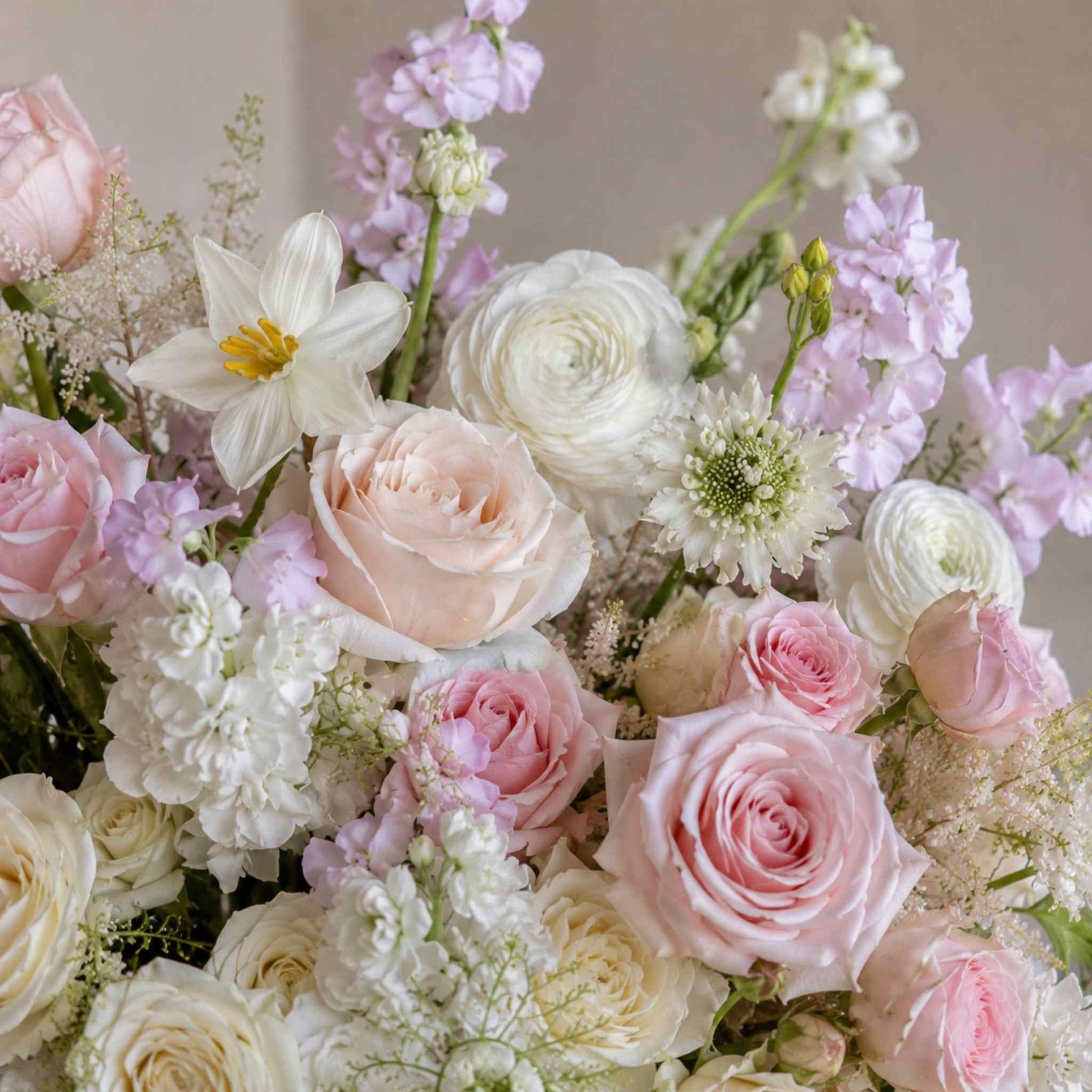 Bouquet of pink, white, and purple flowers with greenery on a neutral background