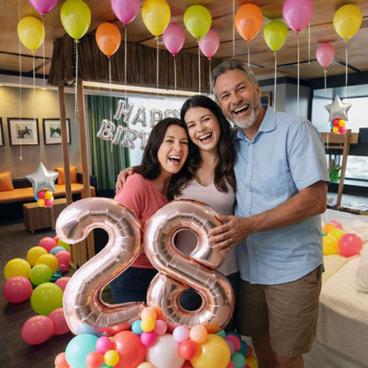 Family celebrating a birthday with colorful balloons and decorations in a living room.