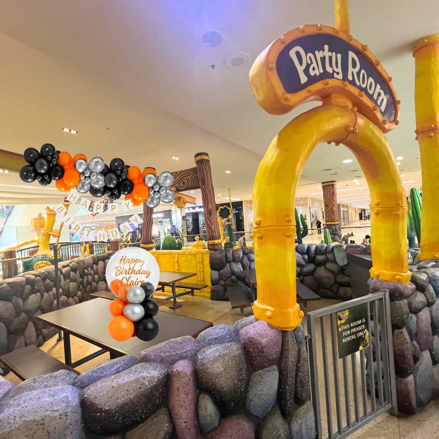 Decorated party room with inflatable arch and balloons in a mall setting