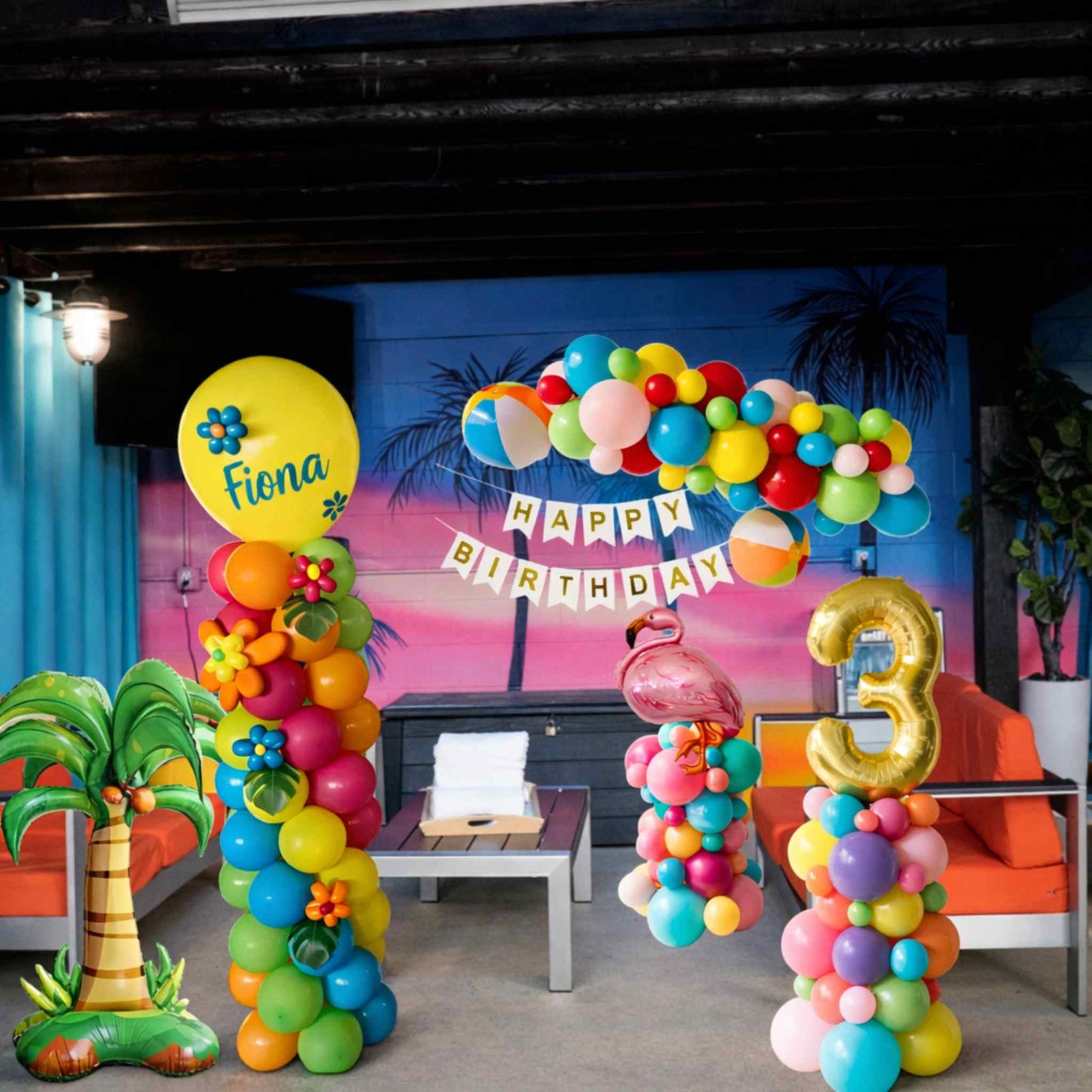 Colorful balloon arch with 'Happy Birthday' banner and number '3' at a birthday party setup.