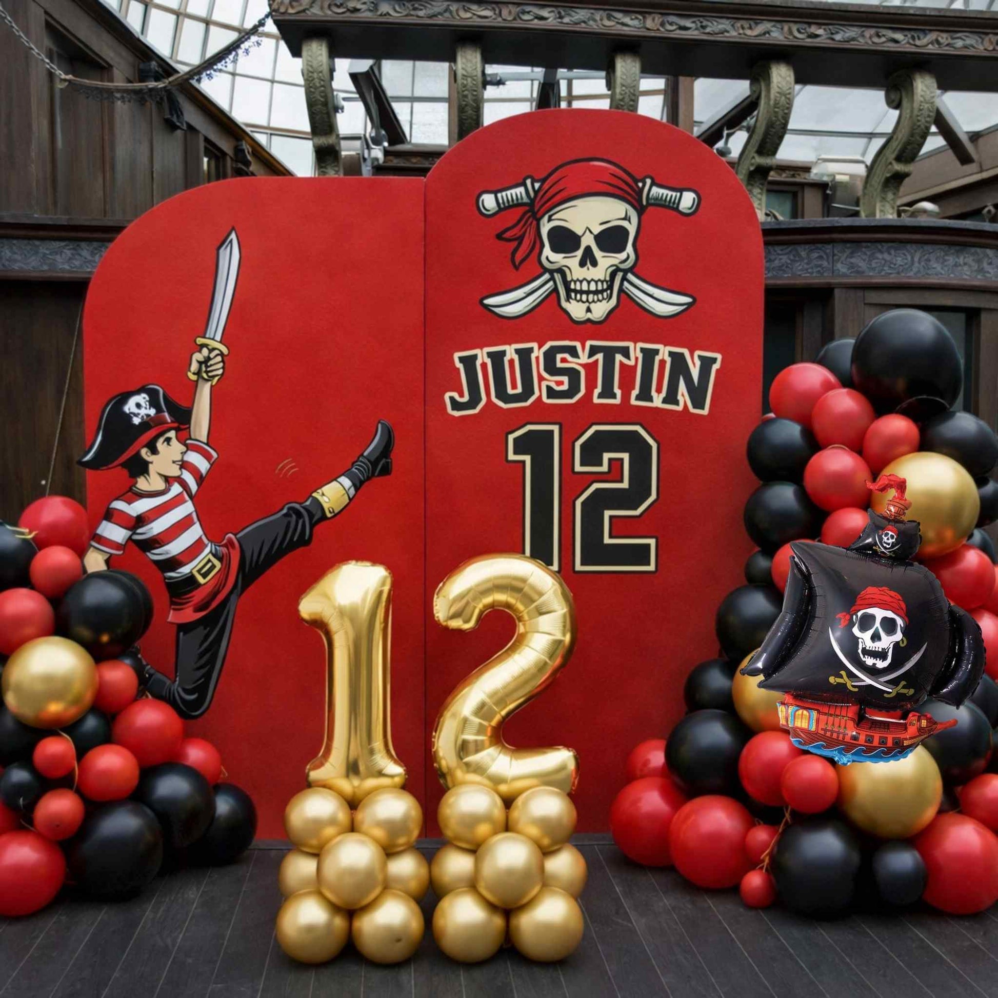 Pirate-themed birthday party setup with red backdrop, gold balloons, and pirate decorations.