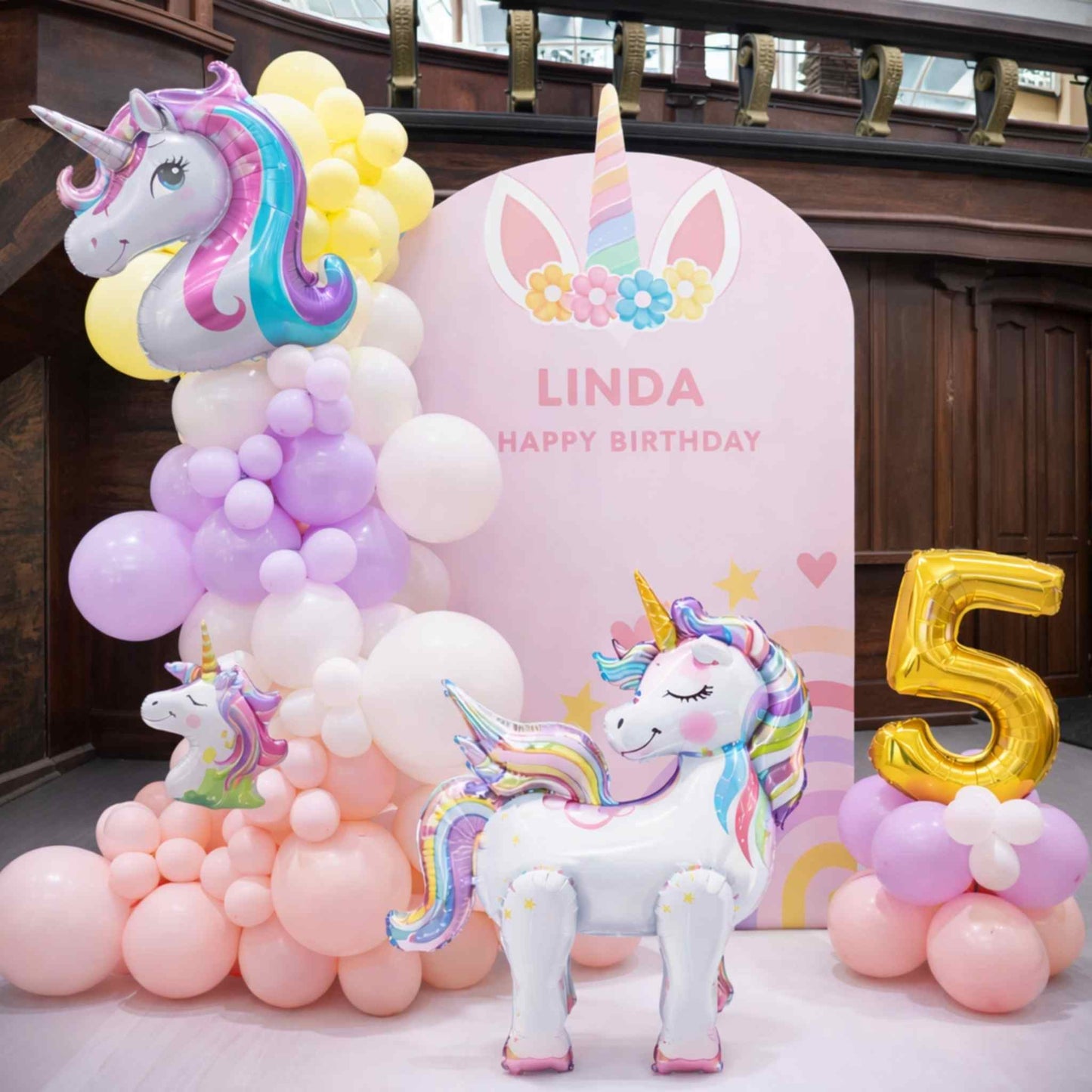 Unicorn-themed birthday party setup with balloons and a pink backdrop.