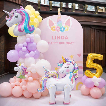 Unicorn-themed birthday party setup with balloons and a pink backdrop.