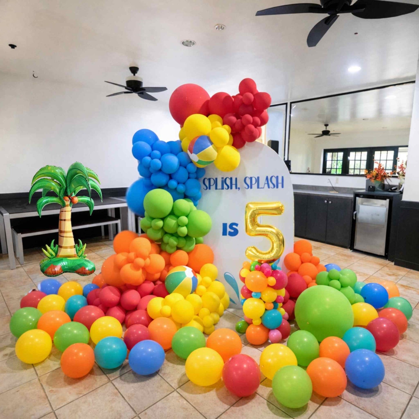 Colorful balloon arch and ball pit setup with 'Splash, Splash is 5' sign in a room.